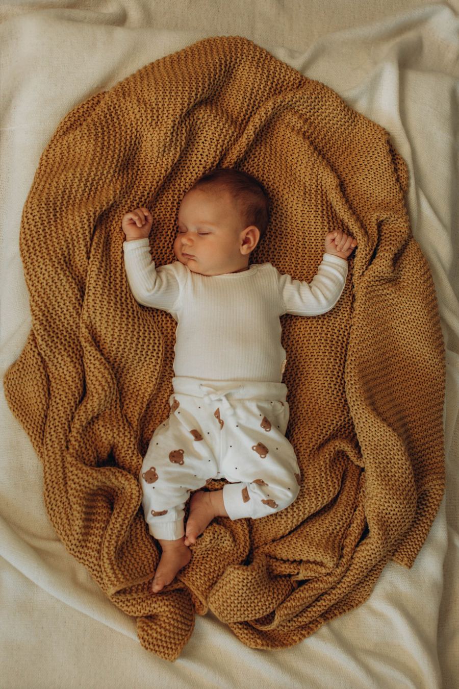 Baby auf Strickdecke in warmen Ockertönen