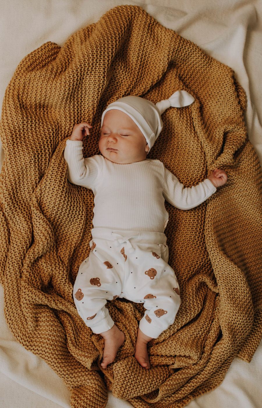 Baby auf Strickdecke in warmen Ockertönen