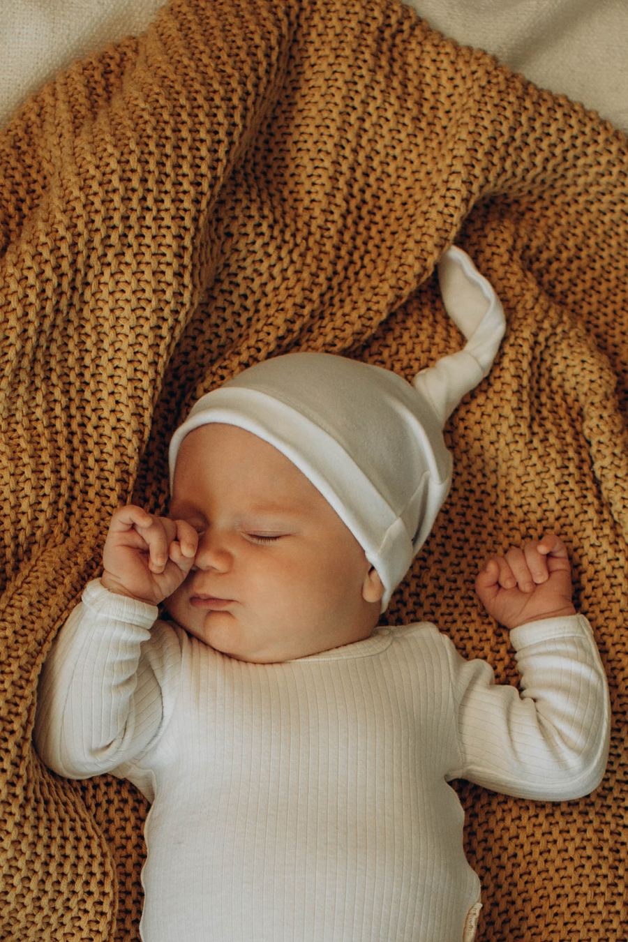 Baby auf Strickdecke in warmen Ockertönen
