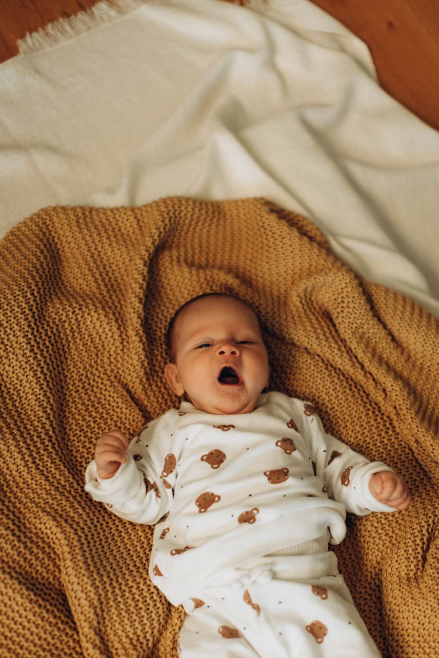 Baby auf Strickdecke in warmen Ockertönen