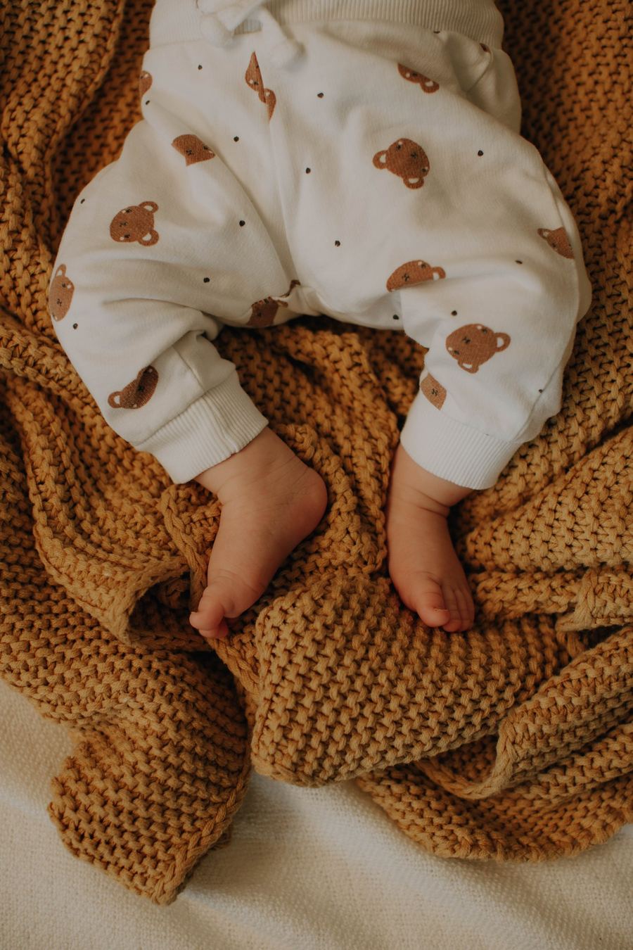 Baby auf Strickdecke in warmen Ockertönen